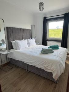 a bedroom with a large bed with two green towels on it at Wallace Lodge in Crieff
