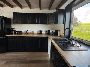 a kitchen with black cabinets and a large window at Wallace Lodge in Crieff