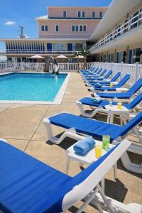 a row of blue and white lounge chairs next to a swimming pool at Beach Colony Motel in Wildwood Crest