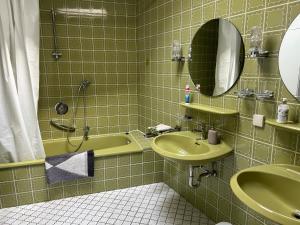 a green tiled bathroom with a sink and a tub at Ferienwohnung Calluna in Buchholz in der Nordheide +9 photos