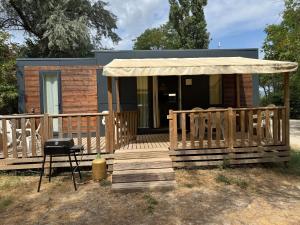 a tiny house with a porch and a grill at Mobil-home val de durance in Cadenet