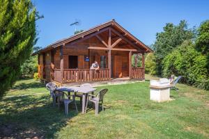 a log cabin with a table and chairs in the yard at Les chalets de fiolles in Brens