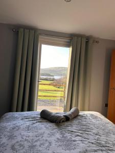 a bed in a bedroom with a large window at Lakeside cottage retreat in Belcoo