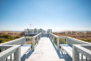 a boardwalk leading to the beach with a pier at Fairwinds by Oak Island Accommodations in Caswell Beach