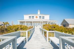 a white house with a boardwalk leading to the beach at Fairwinds by Oak Island Accommodations in Caswell Beach