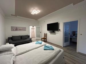 a bedroom with a bed and a couch and a television at JÁZMIN magán szállás in Makó