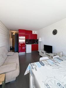 a living room with a bed and a kitchen with red cabinets at Pies de Mer in Fort-Mahon-Plage