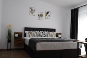 a bedroom with a black and white bed with pillows at Ares Chalet in Horezu