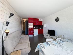 a living room with a couch and a kitchen with red cabinets at Pies de Mer in Fort-Mahon-Plage