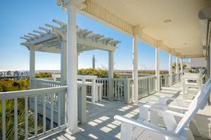 a porch with white chairs and a gazebo at Fairwinds by Oak Island Accommodations in Caswell Beach