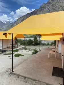 a large yellow tent with chairs and mountains in the background at GoingZero Luxury Camps Jispa in Jispa +7 photos