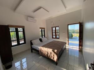 a bedroom with a bed in a room with windows at Pappa's Holidays in Sultan Bathery