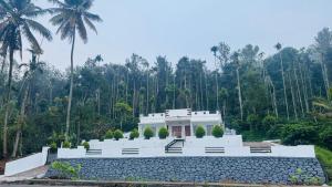 a white house with palm trees in the background at Pappa's Holidays in Sultan Bathery