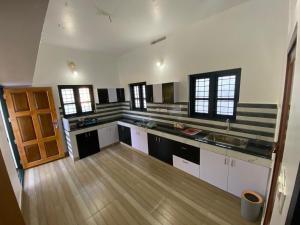 a large kitchen with white cabinets and a wooden floor at Pappa's Holidays in Sultan Bathery