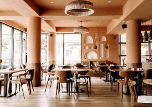 a restaurant with tables and chairs and large windows at NOVO Studio Hotel in Râmnicu Vâlcea
