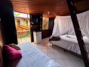 a bedroom with two beds and a tv and a balcony at Beach House NATUREZA self check-in in Itacaré