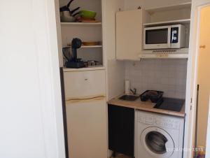 a kitchen with a washing machine and a microwave at les pieds dans l'eau 2 - Piscine chauffée in Le Barcarès