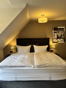 a bedroom with a large white bed with two lamps at Pension Burkhardt in Meißen +57 photos