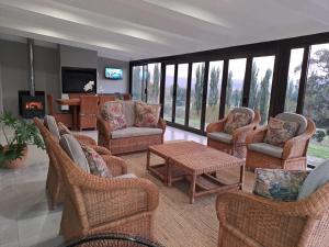 a living room with wicker chairs and a table and a fireplace at 105 Clarens Golf Villa in Clarens