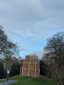 an old brick building in a field with trees at Bedroom 2 with a little loo in King's Lynn