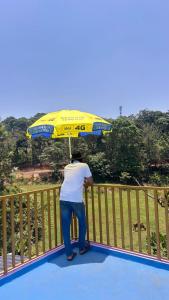 a man standing on a fence with an umbrella at Doddakallu Betta Homestay Coorg in Somvārpet
