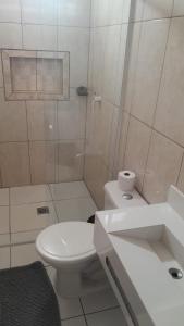 a white bathroom with a toilet and a shower at Pousada Luz do Sol in Penha