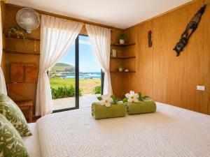 a bedroom with a bed with a view of the ocean at Cabañas & Hostal Tojika in Hanga Roa