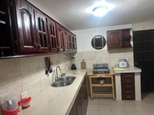 a kitchen with wooden cabinets and a sink and a stove at Departamento con parqueadero céntrico in Baños +6 photos