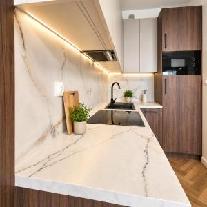 a kitchen with marble countertops and a sink at Olszynki Park Elite Residence in Rzeszów