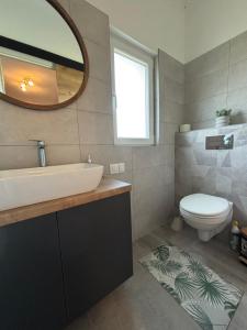 a bathroom with a sink and a toilet and a mirror at JanBar Apartman in Bük