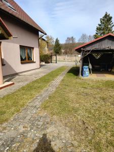 a house with a dirt road next to a building at Apartament Wisełka nad jeziorem in Wisełka