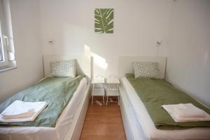 two beds in a small room with a table at Bogárka Apartmanház in Siófok