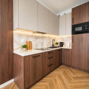 a kitchen with wooden cabinets and a counter top at Olszynki Park Elite Residence in Rzeszów