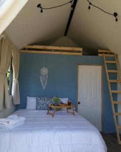 a bed in a room with a blue wall at The Dreamcatcher House Glamping & Cabins Sarchí in Sarchí