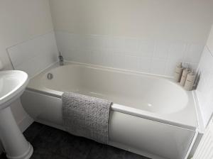 a white bath tub in a bathroom with a sink at Modern spacious private detached house in Beeston +61 photos