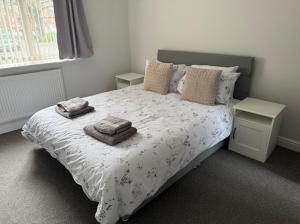 a bedroom with a bed with towels on it at Modern spacious private detached house in Beeston