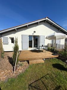 a house with a deck with a table and an umbrella at L'Anse Blanche in Biganos