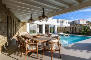 a dining room with a table and chairs and a pool at Splendid Mykonos Luxury Villas & Suites in Mikonos