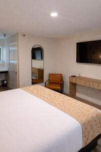 ein Hotelzimmer mit einem großen Bett und einem Stuhl in der Unterkunft The Alcala Hotel Mission Valley Seaworld in San Diego