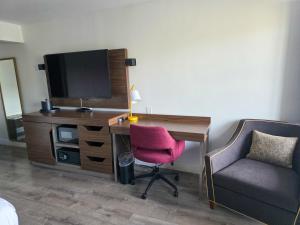 a bedroom with a desk with a tv and a chair at Penn Lodge Hotel & Suites Philadelphia - Bensalem in Bensalem