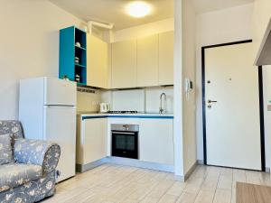 a kitchen with a white refrigerator and a couch at 80 Trilocale al Barbara in Lido Adriano