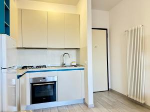 a kitchen with white cabinets and a sink and a refrigerator at 80 Trilocale al Barbara in Lido Adriano