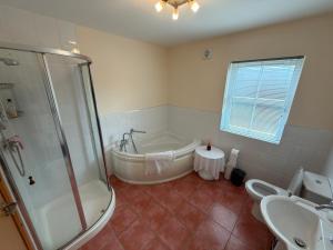 a bathroom with a tub and a shower and a sink at 10 Mill Square in Portstewart +25 photos