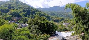 a village in the mountains with trees and houses at La Cabañita VIP Amanecer in Minca
