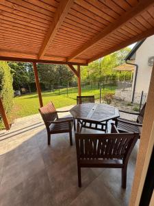 a patio with a wooden pergola and a table and chairs at JanBar Apartman in Bük