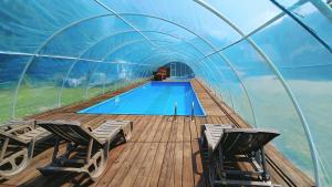 a swimming pool on a boat with chairs and a tunnel at Agroturystyka Gościniec Ethoria in Łomnica