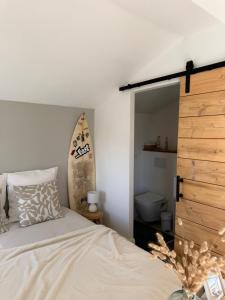 a bedroom with a bed and a surfboard on the wall at L'Anse Blanche in Biganos
