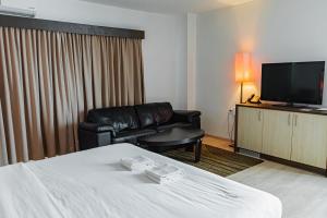 a hotel room with a bed and a couch and a television at Queens Hotel in Paramaribo