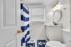 a white bathroom with a blue and white shower curtain at Sunkissed 2 by Oak Island Accommodations in Oak Island