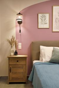 a bedroom with pink walls and a bed and a nightstand at Eftychia's Cozy Apartment in Sitia